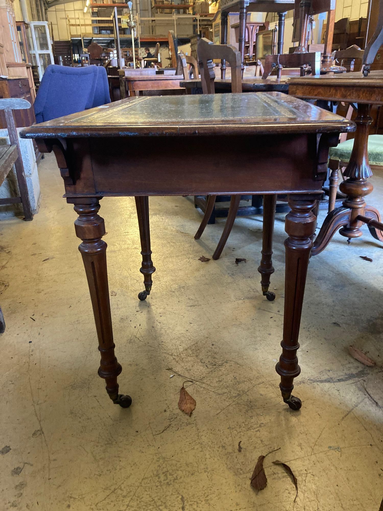 A late Victorian mahogany writing table, with leather lined top and ceramic castors, width 88cm